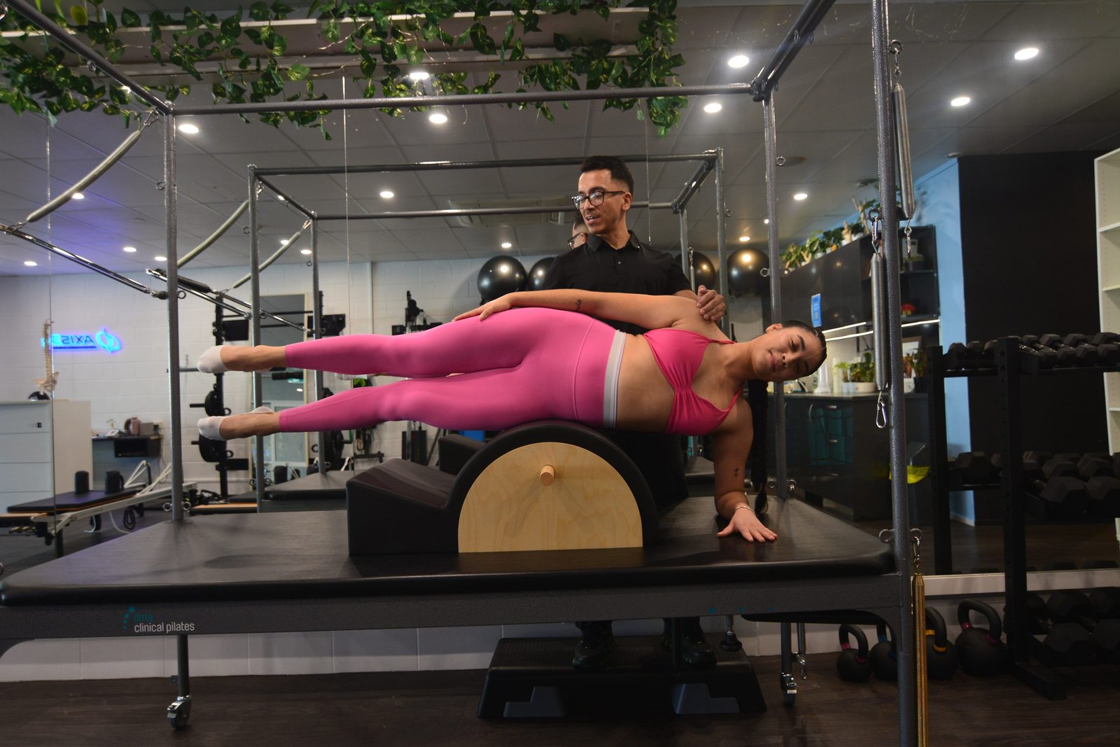 Luis coaching a client through a side-plank exercise on the Cadillac at Axis33