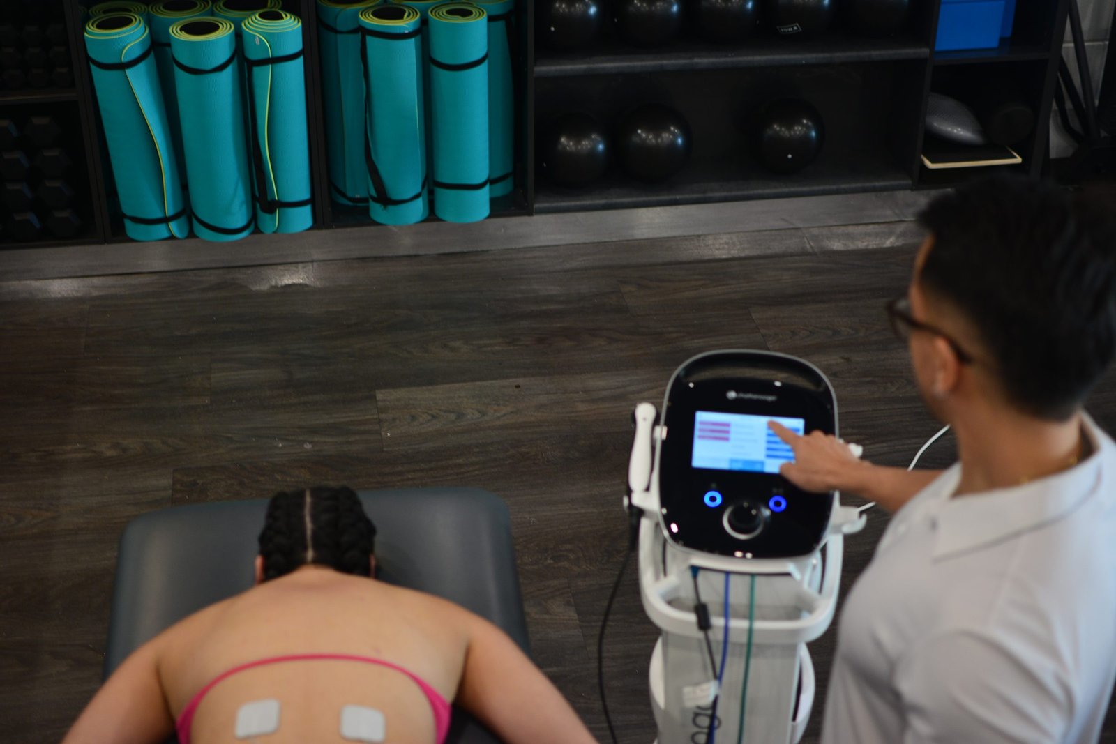 A physiotherapist at Axis33 setting up electrical stimulation treatment for a patient